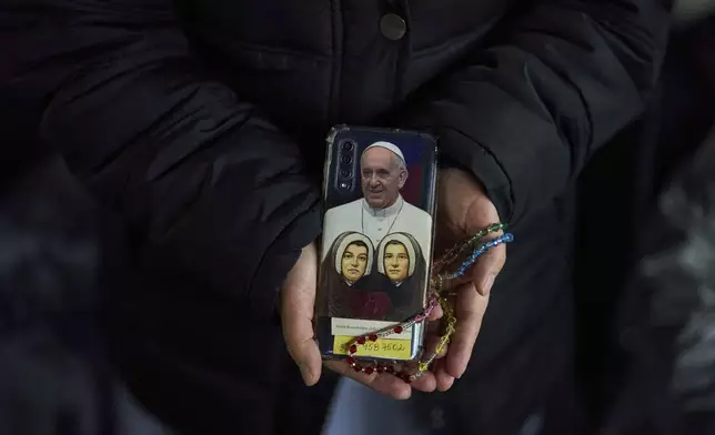 A Catholic nun shows the back cover of her mobile phone with a photograph of Pope Francis as she attends a nightly rosary prayer service for Pope Francis in St. Peter's Square at the Vatican, Thursday, March 6, 2025. (AP Photo/Francisco Seco)
