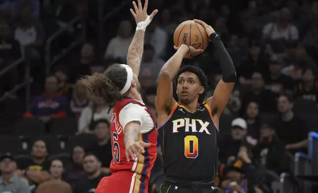 Phoenix Suns forward Ryan Dunn (0) looks to shoot over New Orleans Pelicans guard Jose Alvarado, left, during the first half of an NBA basketball game, Friday, Feb. 28, 2025, in Phoenix. (AP Photo/Rick Scuteri)