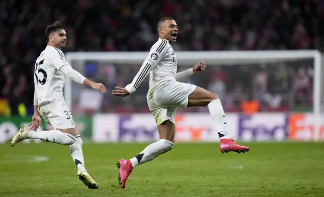 Real Madrid's Kylian Mbappe and Raul Asencio, left, run celebrating after a penalty shootout at the end of the Champions League round of 16, second leg, soccer match between Atletico Madrid and Real Madrid at the Metropolitano stadium in Madrid, Spain, Wednesday, March 12, 2025. (AP Photo/Manu Fernandez)