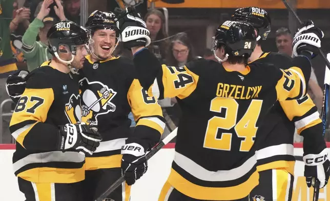 Pittsburgh Penguins' Rickard Rakell (67) celebrates with Sidney Crosby (87) after scoring during the second period of an NHL hockey game against the New Jersey Devils in Pittsburgh, Saturday, March 15, 2025. (AP Photo/Gene J. Puskar)