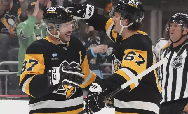 Pittsburgh Penguins' Rickard Rakell (67) celebrates with Sidney Crosby after scoring during the second period of an NHL hockey game against the New Jersey Devils in Pittsburgh, Saturday, March 15, 2025. (AP Photo/Gene J. Puskar)