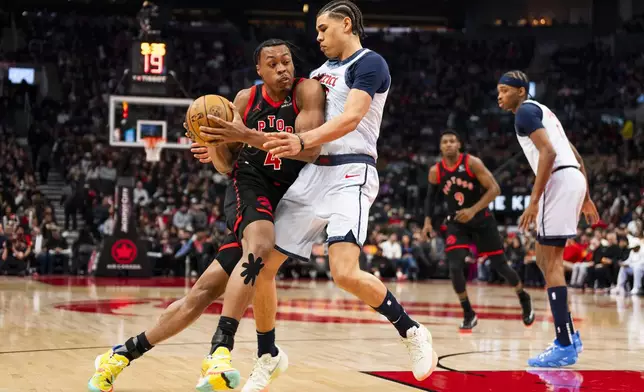 Toronto Raptors guard Scottie Barnes (4) drives the net against defending Washington Wizards forward Kyshawn George (18) during the first half of NBA action in Toronto on Saturday, March 8, 2025. (Thomas Skrlj/The Canadian Press via AP)