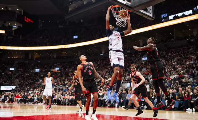 Washington Wizards guard Bilal Coulibaly (0) dunks the ball as Toronto Raptors guard RJ Barrett (9) and guard Jared Rhoden (8) during the second half of NBA action in Toronto on Saturday, March 8, 2025. (Thomas Skrlj/The Canadian Press via AP)