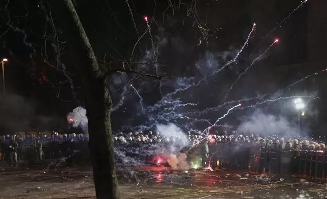 Fireworks thrown by protesters explode over riot police during a protest against the arrest of Istanbul's Mayor Ekrem Imamoglu, in Istanbul, Turkey, Saturday, March 22, 2025. (AP Photo/Francisco Seco)