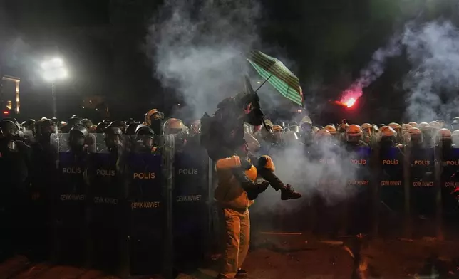 Protesters stand in front of riot police during a protest against the arrest of Istanbul's Mayor Ekrem Imamoglu, in Istanbul, Turkey, Saturday, March 22, 2025. (AP Photo/Khalil Hamra)