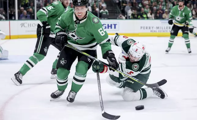 Dallas Stars center Mikael Granlund (64) and Minnesota Wild defenseman Jake Middleton (5) attempt to control the puck during an NHL hockey game in Dallas, Monday, March 24, 2025. (AP Photo/Gareth Patterson)