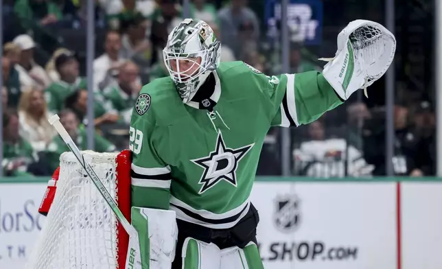 Dallas Stars goaltender Jake Oettinger signals to his team during an NHL hockey game against the Minnesota Wild in Dallas, Monday, March 24, 2025. (AP Photo/Gareth Patterson)