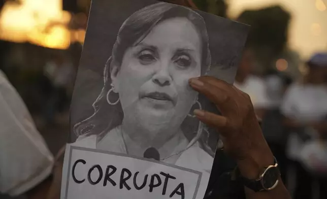A protester holds a photo of Peru's President Dina Boluarte marked with the Spanish word for corrupt during a march to demand the government provide security against the rising violence in Lima, Peru, Friday, March 21, 2025. (AP Photo/Guadalupe Pardo)