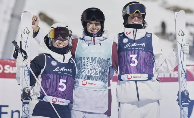 France's Perrine Laffont, center, gold medalist in a women's moguls at the Freestyle World Championships celebrates with silver medalist Japan's Hinako Tomitaka, left, and bronze medalist Canada's Maia Schwinghammer, in St. Moritz, Switzerland, Wednesday, March 19, 2025. (Gian Ehrenzeller/Keystone via AP)