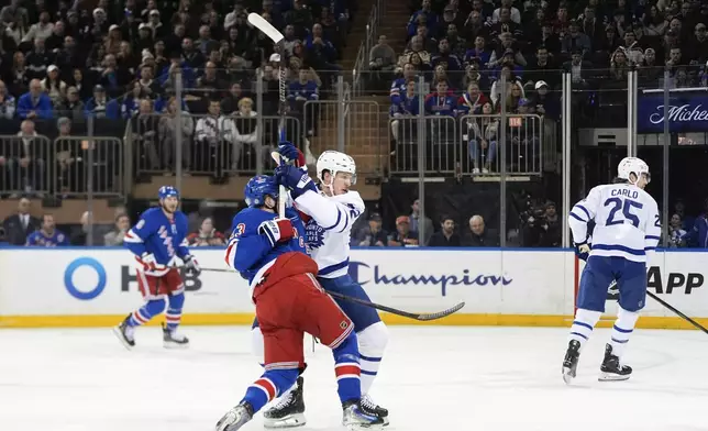 New York Rangers left wing Alexis Lafrenière, center left, and Toronto Maple Leafs defenseman Jake McCabe, center right, right, collide during the first period of an NHL hockey game Thursday, March 20, 2025, in New York. (AP Photo/Julia Demaree Nikhinson)