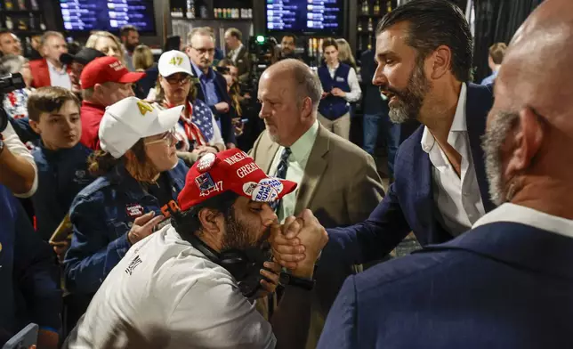 A man kisses the hand of Donald Trump Jr. as he greets supporters after a town hall meeting Monday, March 17, 2025, in Oconomowoc, Wis. (AP Photo/Jeffrey Phelps)