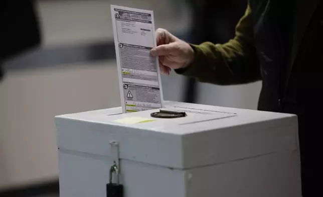 A man places his ballot in a box during early voting in Waukesha, Wis Tuesday, March 18, 2025. (AP Photo/Jeffrey Phelps)