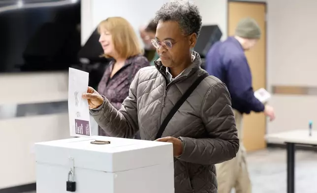 A woman places her ballot in a box during early voting in Waukesha, Wis., Tuesday, March 18, 2025. (AP Photo/Jeffrey Phelps)