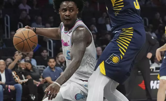 Miami Heat guard Davion Mitchell (45) looks to pass the ball under pressure from Indiana Pacers center Myles Turner (33) during the first half of an NBA basketball game, Friday, Feb. 28, 2025, in Miami. (AP Photo/Marta Lavandier)