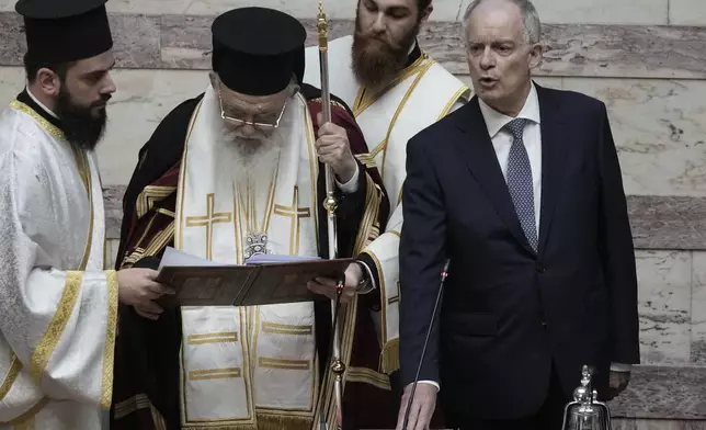 Greece's new President Constantine Tassoulas, right, takes an oath next to Archbishop of Athens and All Greece Ieronimos during the swearing in ceremony at the Parliament, in Athens, Greece, Thursday, March 13, 2025. (AP Photo/Thanassis Stavrakis)