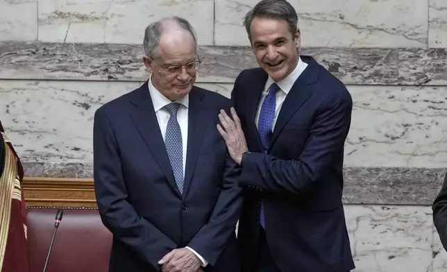 Greece's Prime Minister Kyriakos Mitsotakis, right, hugs the new President Constantine Tassoulas during the swearing in ceremony at the Parliament, in Athens, Greece, Thursday, March 13, 2025. (AP Photo/Thanassis Stavrakis)