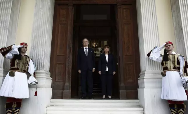 Outgoing Greek President Katerina Sakellaropoulou, center right, and the new President Constantine Tassoulas, center left, stand for the national anthem during the handover ceremony at the presidential palace in Athens, Greece, Thursday, March 13, 2025. (Yannis Kolesidis/Pool via AP)
