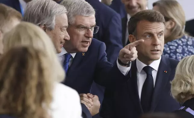 FILE - From left, United Nations' Secretary-General Antonio Guterres, the President of the International Olympic Committee (IOC) Thomas Bach and French President Emmanuel Macron speak, as they arrive, in Paris, France, for the opening ceremony of the 2024 Summer Olympics, Friday, July 26, 2024. (Ludovic Marin/Pool Photo via AP, File)