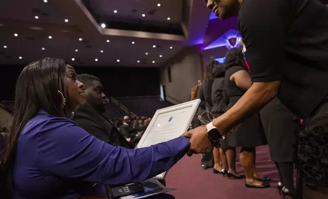 Diamond, daughter of Angie Stone, receives a plaque in honor of her mother at a memorial service, Friday, March 14, 2025, in Austell. Ga. (AP Photo/Olivia Bowdoin)