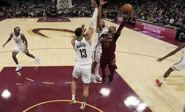 Cleveland Cavaliers guard Darius Garland (10) shoots as Brooklyn Nets guard Tyrese Martin (13) and forward Trendon Watford, center, defend in the second half of an NBA basketball game, Tuesday, March 11, 2025, in Cleveland. (AP Photo/Sue Ogrocki)