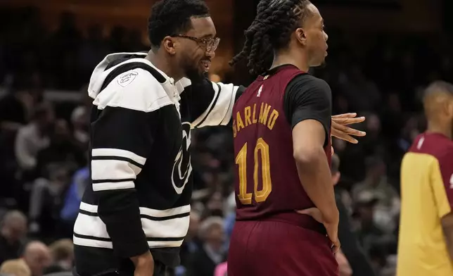 Cleveland Cavaliers guard Donovan Mitchell, left, who did not dress for the game, talks with teammate Darius Garland (10) in the second half of an NBA basketball game against the Brooklyn Nets, Tuesday, March 11, 2025, in Cleveland. (AP Photo/Sue Ogrocki)