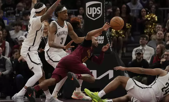 Cleveland Cavaliers guard Darius Garland, center, passes between Brooklyn Nets guard Keon Johnson, left, Nic Claxton, second from left, and Cam Thomas (24) in the second half of an NBA basketball game, Tuesday, March 11, 2025, in Cleveland. (AP Photo/Sue Ogrocki)