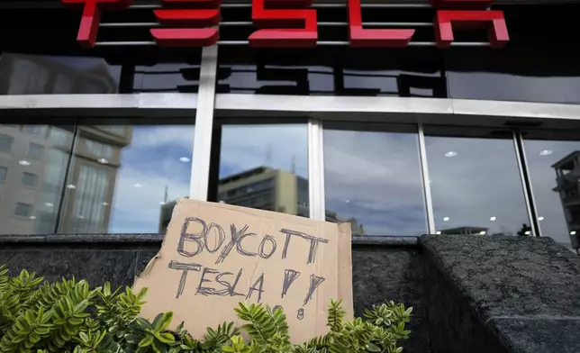 A banner is left outside a Tesla showroom during a demonstration, in Lisbon, Sunday, March 9, 2025. (AP Photo/Armando Franca)