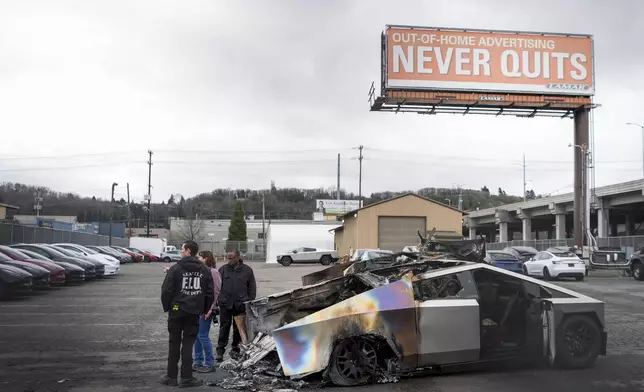 ATF investigators and a member of the Seattle Fire Department inspect burned Tesla Cybertrucks at a Tesla lot in Seattle, Monday, March 10, 2025. (AP Photo/Lindsey Wasson)