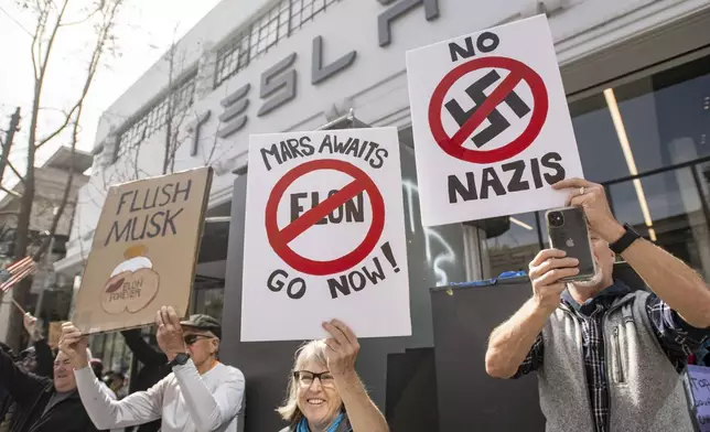 Protesters rally outside a Tesla dealership in San Francisco, Saturday, March 15, 2025. (AP Photo/Josh Edelson)