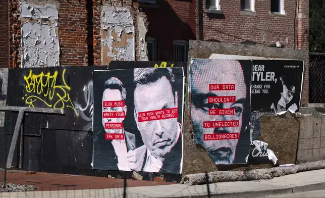 Posters showing the face of Elon Musk and messages relating to data privacy are seen on a fence surrounding a building site in Washington, Friday, March 7, 2025. (AP Photo/Ben Curtis)