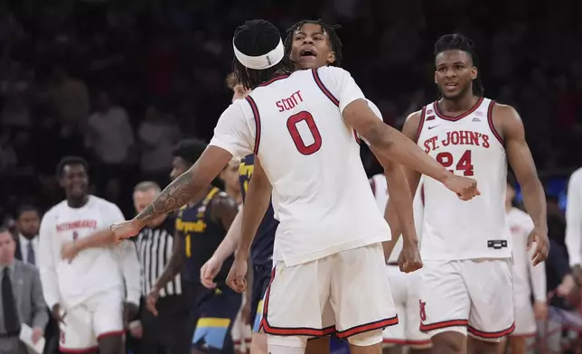 St. John's's Aaron Scott (0) celebrates with Simeon Wilcher and Zuby Ejiofor (24) during the second half of an NCAA college basketball game against the Marquette in the semifinals of the Big East tournament Friday, March 14, 2025, in New York. (AP Photo/Frank Franklin II)