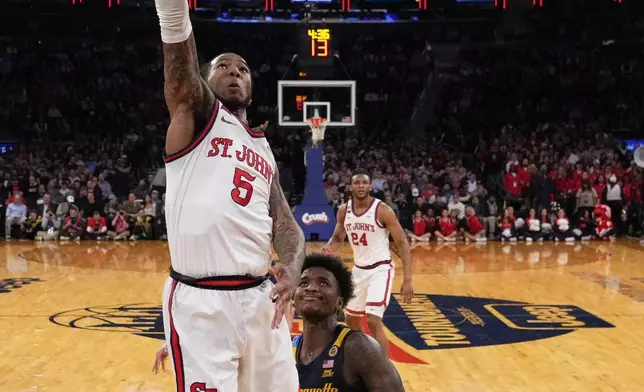 St. John's's Deivon Smith (5) drives past Marquette's Kam Jones (1) during the first half of an NCAA college basketball game in the semifinals of the Big East tournament Friday, March 14, 2025, in New York. (AP Photo/Frank Franklin II)