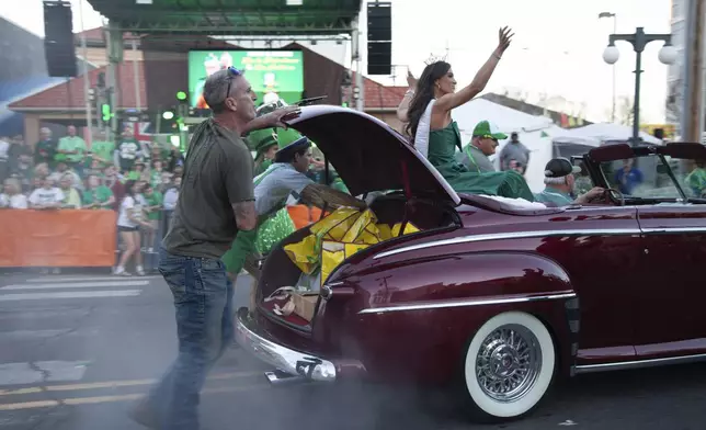 Volunteers push a broken-down car at the 22nd Annual World's Shortest St. Patrick's Day Parade on Monday, March 17, 2025, in Hot Springs, Ark. (AP Photo/Katie Adkins)