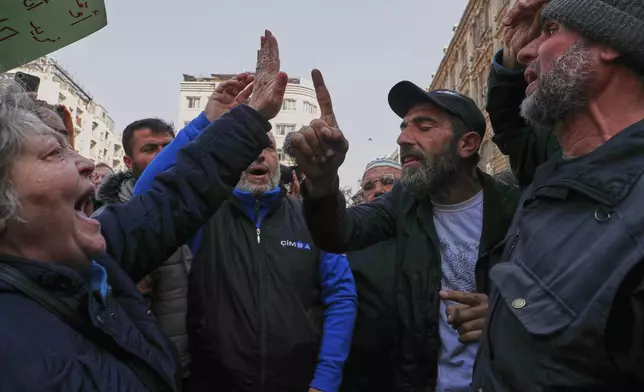 An activist woman protesting against the recent wave of violence and sectarian attacks in Syria's coastal region faces off against a man at Al Marjeh Square in Damascus, Syria, Sunday, March 9, 2025. (AP Photo/Omar Sanadiki)