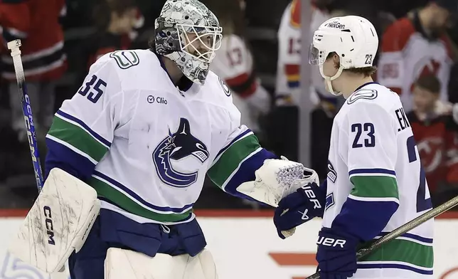 Vancouver Canucks goaltender Thatcher Demko congratulates Jonathan Lekkerimaki (23) who scored the game winning goal during a shootout of an NHL hockey game against the New Jersey Devils Monday, March 24, 2025, in Newark, N.J. (AP Photo/Adam Hunger)