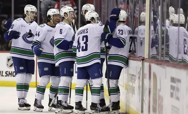 Vancouver Canucks right wing Jonathan Lekkerimaki (23) is congratulated by teammates after scoring the winning goal during a shootout of an NHL hockey game against the New Jersey Devils, Monday, March 24, 2025, in Newark, N.J. (AP Photo/Adam Hunger)
