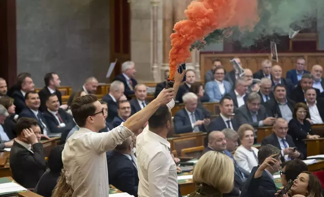 MPs of Momentum protest with flares during the plenary session of the Hungarian parliament in Budapest, Hungary, Tuesday, March 18, 2025. (Boglarka Bodnar/MTI via AP)