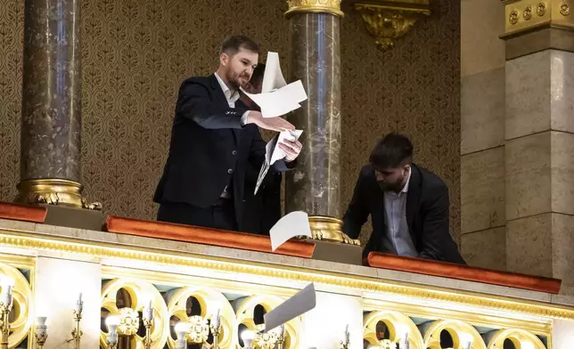 Ferenc Gelencser of Momentum, left, throws pamphlets from the balcony during the plenary session of the Hungarian parliament in Budapest, Hungary, Tuesday, March 18, 2025. (Boglarka Bodnar/MTI via AP)