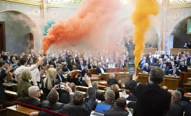 MPs of Momentum protest with flares during the plenary session of the Hungarian parliament in Budapest, Hungary, Tuesday, March 18, 2025. (Boglarka Bodnar/MTI via AP)