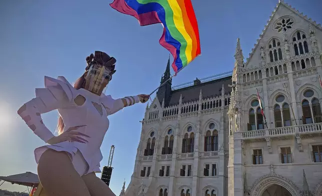 FILE - A participant waves a rainbow flag during an LGBT rights demonstration in front of the Hungarian Parliament building in Budapest, Hungary on June 14, 2021. (AP Photo/Bela Szandelszky, File)
