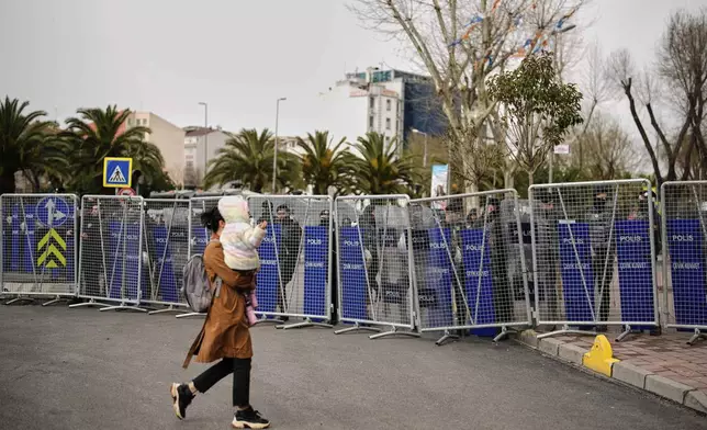 A woman walks past police cordons blocking the roads leading to the Vatan Security Department, where Istanbul Mayor Ekrem Imamoglu is expected to be taken following his arrest in Istanbul, Turkey, Wednesday, March 19, 2025. (AP Photo/Emrah Gurel)