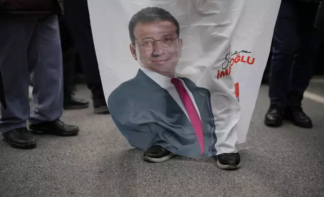 People gather, holding a banner featuring a photo of Istanbul Mayor Ekrem Imamoglu, to protest his arrest in Istanbul, Turkey, Wednesday, March 19, 2025. (AP Photo/Emrah Gurel)
