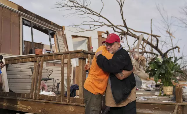 Tim Scott, right, gets a hug from friend Jorden Harris outside Scott's home he was inside when it was destroyed during a severe storm the evening before Saturday, March 15, 2025, in Wayne County, Mo. (AP Photo/Jeff Roberson)