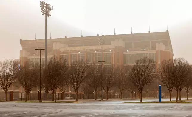 The Oklahoma Memorial Stadium on the campus of the University of Oklahoma is seen covered by dusk and smoke as wildfires spread across Oklahoma on Friday, March 14, 2025. (AP Photo/Alonzo Adams)