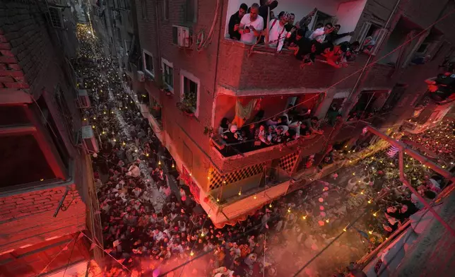 Residents of Ezbet Hamada in Cairo's El Matareya district peer from their balconies to celebrate a mass break-fast, "Iftar", the meal to end their fast at sunset, during the holy fasting month of Ramadan in Cairo, Egypt, Saturday, March 15, 2025. (AP Photo/Amr Nabil)
