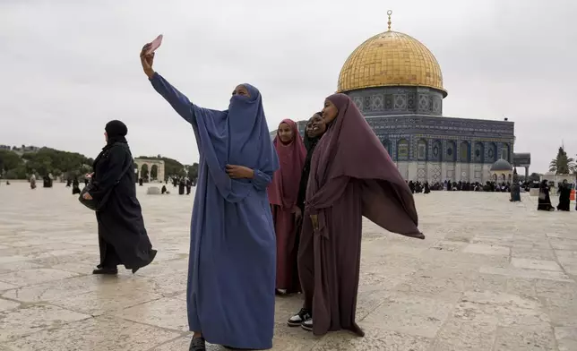 Palestinian women take a photo next to the the Dome of the Rock shrine at the Al-Aqsa Mosque compound in the Old City of Jerusalem, during the Muslim holy month of Ramadan, Friday, March 14, 2025. (AP Photo/Mahmoud Illean)
