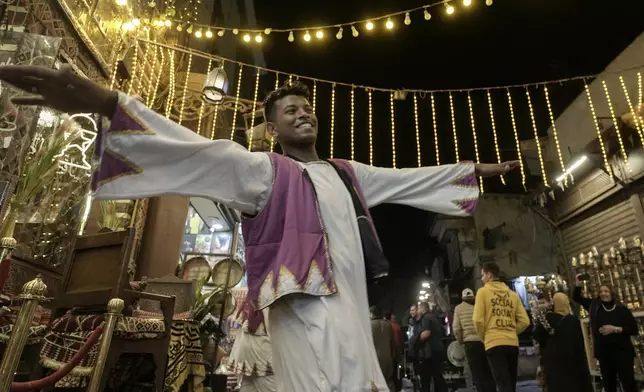 A dancer performs a Nubian dance to attract customers to enter a restaurant for a "Suhur" meal, before they start their fast during the holy fasting month of Ramadan, at El-Gamaliyya district in Cairo, Egypt, Tuesday, March 11, 2025. (AP Photo/Amr Nabil)