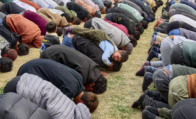 Kashmiri Muslims pray, as a boy plays on the back of his father, during the first Friday of the fasting month of Ramadan outside the Jamia Masjid or Grand Mosque in Srinagar, Indian controlled Kashmir, Friday, March 7, 2025. (AP Photo/Dar Yasin)