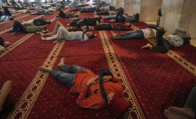 Muslim men rest after the first Friday prayer of the fasting month of Ramadan at Istiqlal Mosque in Jakarta, Indonesia, Friday, March 7, 2025. (AP Photo/Tatan Syuflana)