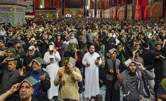 Shiite worshippers place copies of the Quran on their heads during Laylat al-Qadr, or the Night of Destiny, in the holy fasting month of Ramadan at the shrine of Imam Ali shrine in Najaf, Iraq, Wednesday, March 19, 2025. (AP Photo/Anmar Khalil)